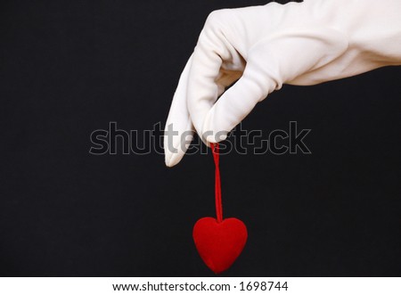 hand in white glove holding a red heart as symbol of love