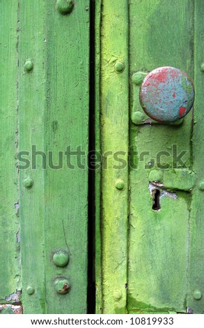 detail in close-up of an old wood green door with knob and keyhole