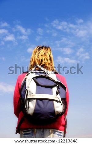 woman traveling with a backpack standing in rest in front of a blue sky