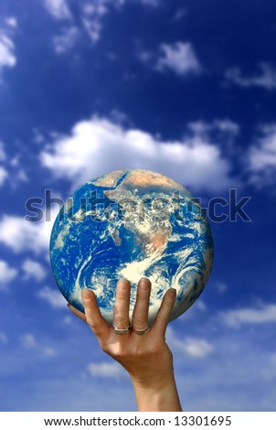 woman hand holding a planet earth globe in front of a blue sky