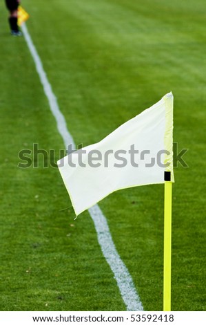 flag on a soccer pitch and linesman referee back far away along the line