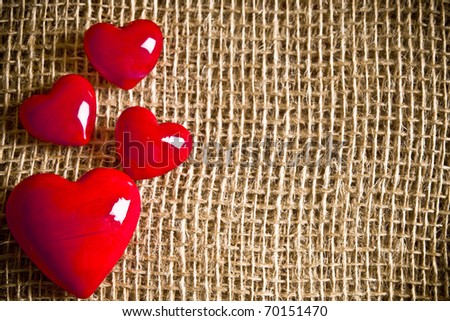 four red hearts over burlap background with copy space like a Valentine love concept