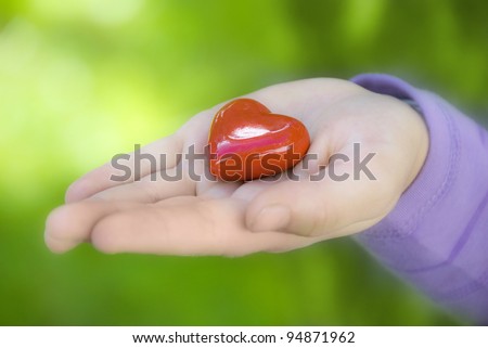 a child hand with red heart on palm like a concept of love for mother´s day, love for God or love for nature and environment