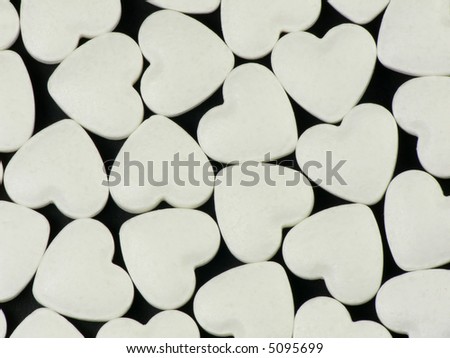 Heart-shaped pills on black background