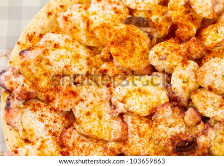 cooked octopus slices dressed with paprika over wooden plate, top view