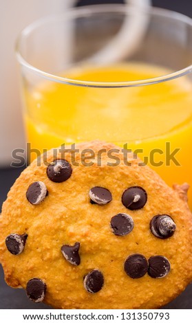 Pumpkin cookie with chocolate in focus, orange juice and coffee in the background