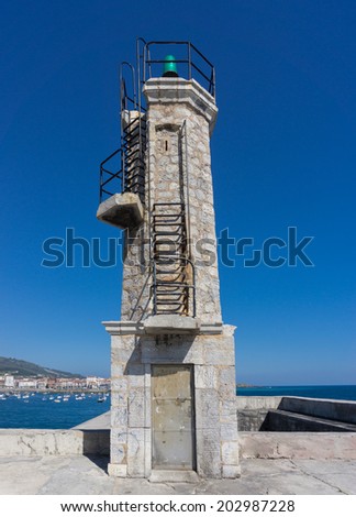 Old small stone lighthouse over blue sky