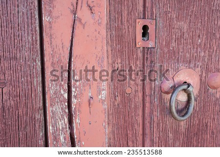 Closeup of vintage run-down wooden door iron lock (red painted)