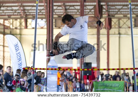 VALENCIA, SPAIN - APRIL 16: Amateur Inline Skater doing acrobatics and jumping over a bar in the roller skate exhibition day celebrated each year on April 16, 2011 in Valencia, Spain
