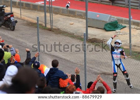 CHESTE, SPAIN  - NOVEMBER 6: Maverick Viñales of Pev-Blusens-SMX-Paris Hilton throws his gloves to the crowd ini celebration of the final race of MotoGP Grand Prix 2011 on November 6, 2011 in Cheste (Valencia), Spain