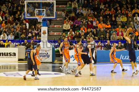 VALENCIA, SPAIN - JANUARY 28: Carlos Jimenez (blue shirt #10) throws for a three-point basket during the ACB league match between Valencia Basket  and Asefa Estudiantes, 85-71, on January 28, 2012, in Valencia, Spain