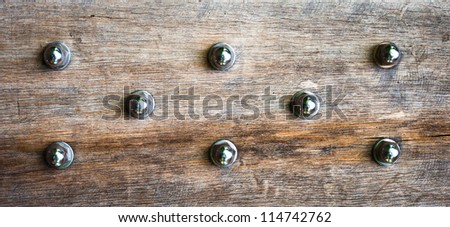 Close up of wood panel studded with bolts