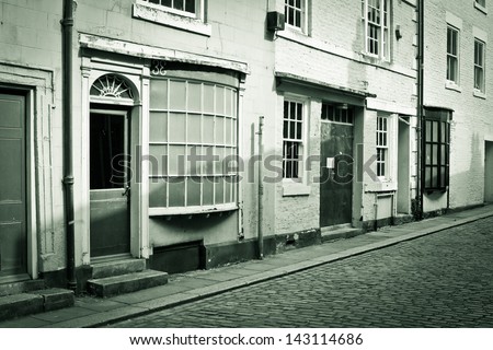 Buildings on a cobbled street in England in sepia tones