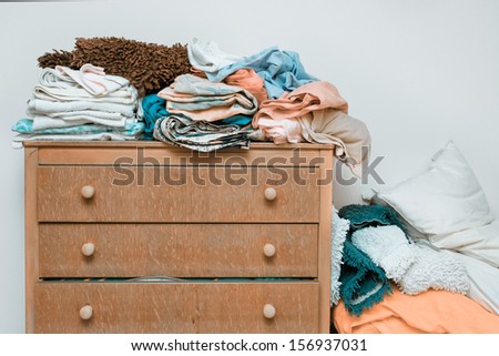 Piles of bed linen on a wooden chest of drawers
