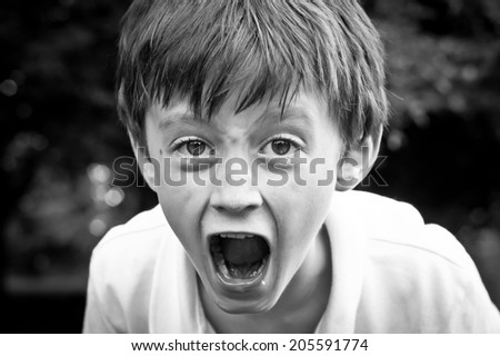 A dramatic monochrome image of an angry six year old boy