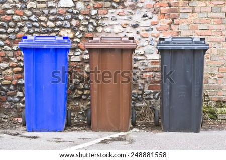 Three plastic bins against a stone wall