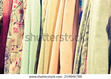 Close up of women's scarves hanging in a store  with vintage filter applied