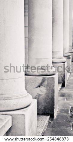 Row of stone pillars on the outside of an urban building in black and white