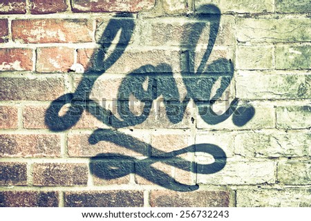 Love in graffiti paint on a brick wall with retro filter applied