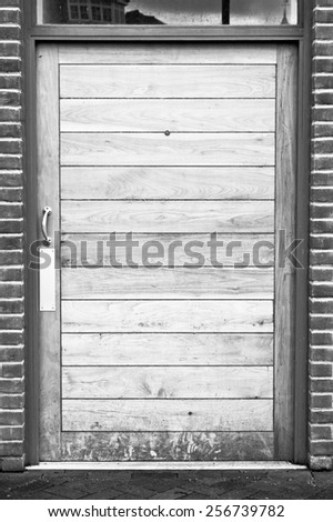 A modern wooden door in a brick building in black and white