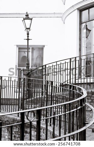 Metal railings and an old fashioned street lamp in black and white