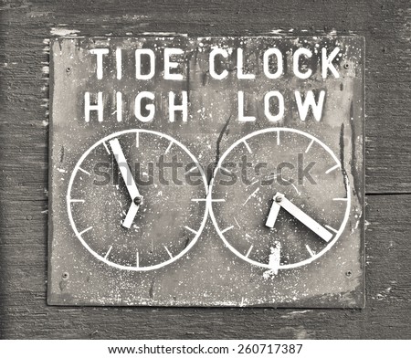 A clock indicating tidal times in Dunwich, UK, in sepia tones