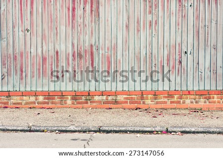Blue and orange paint on a fence with a brick base