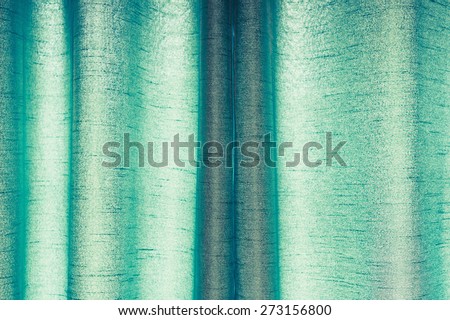 Part of a drawn pair of green curtains made from synthetic material