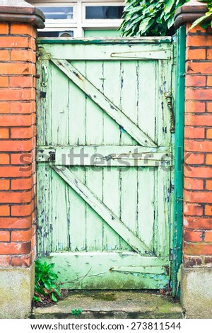 A weathered wooden garden gate in a red brick wall in the UK