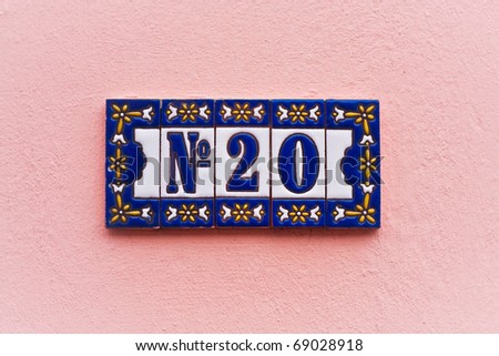 Ornate house number tiles on a pink wall, subtle white vignette adds impact
