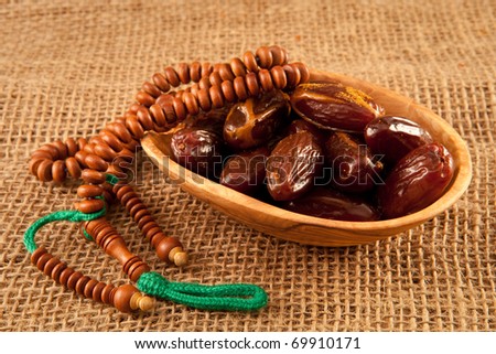This an image of dates with islamic prayer beads for context- dates are traditionally used to break the fast in Ramadan and the beads suggest a spiritual theme to the image