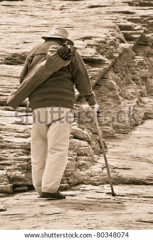 Old man walking with a stick on rocks