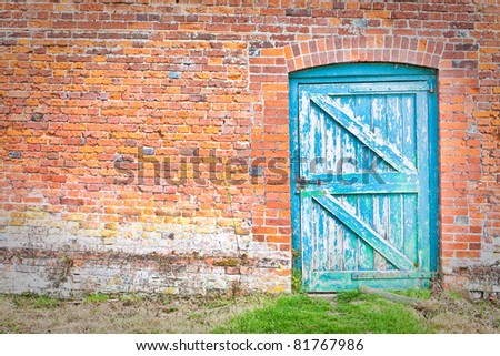 A quirky blue door set at an odd angle in a red brick wall in an English country garden