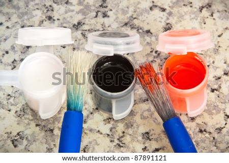 Paint brushes and paint pots on a marble surface