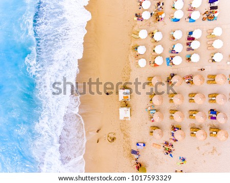 Sun chairs and umbrellas bird\'s eye view on sand beach in Greece