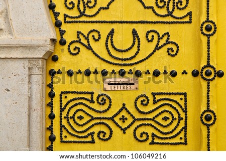 Beautiful traditional yellow door of Tunisia with black ornaments