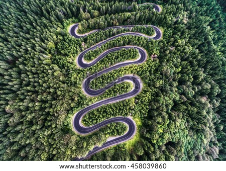 Winding road from the high mountain pass in Transylvania, Romania. Great road trip trough the dense woods. Aerial view.