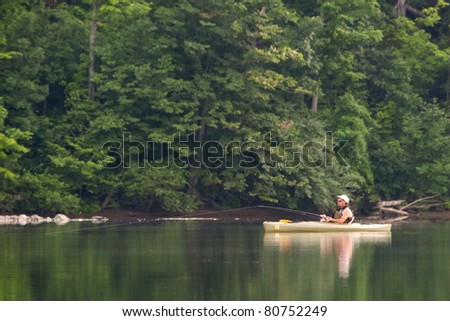 an angler fishing from a kayak on a calm rural lake