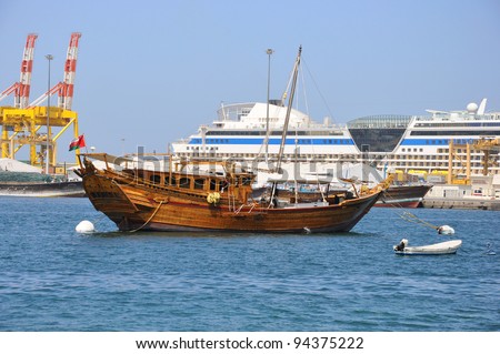 A traditional fishing dhow is anchored in Muscat Harbor, Oman. Cruise ship  is in background.