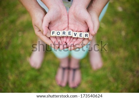 Loving young couple holding letters from a board game to spell out the word forever.