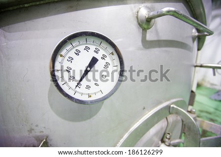 Wide angle close up view of a temperature gauge mounted on a stainless steel tank in a winery in the Breede Valley in the Western Cape of South Africa