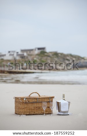 Picnic basket on a beach with a bottle of white wine in a stainless steel cooler