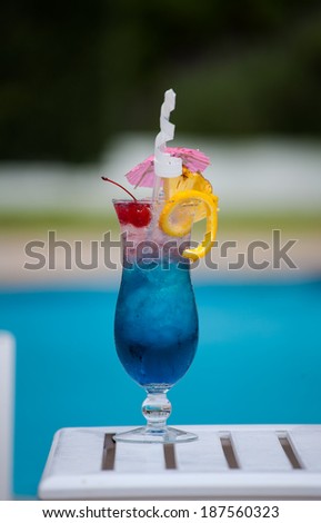 Single blue cocktail in a cocktail glass on a table by the pool at a holiday resort in South Africa