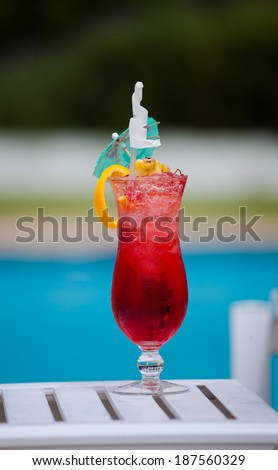 Single red cocktail in a cocktail glass on a table by the pool at a holiday resort in South Africa