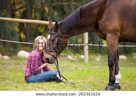 Sexy Blond farm girl sitting with her horse on a farm in South Africa