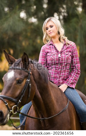 Sexy blond farm girl riding her horse on a farm in South Africa