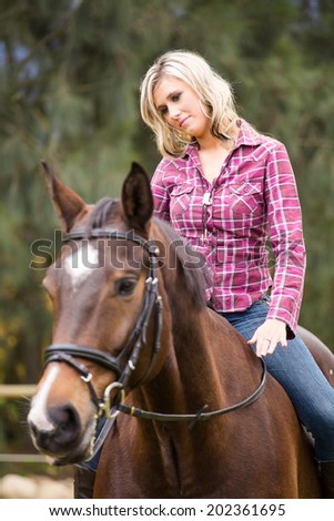 Sexy blond farm girl riding her horse on a farm in South Africa