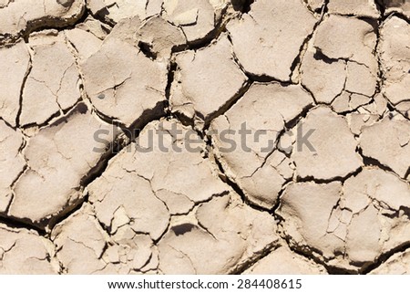 Close up image of dry and cracked clay in an old riverbed in the hot african sun. To be used for textures or backgrounds.