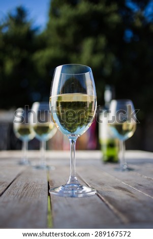 Close up wide angle   shot of a glass of white whine on a rustic table outside with natural light