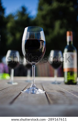 Close up wide angle  shot of a glass of red whine on a rustic table outside with natural light